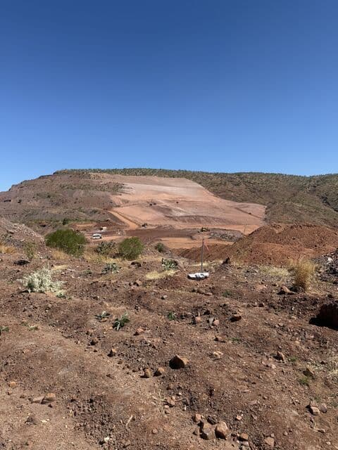 Earthworks pad cut into a hillside with survey pegs marking the line